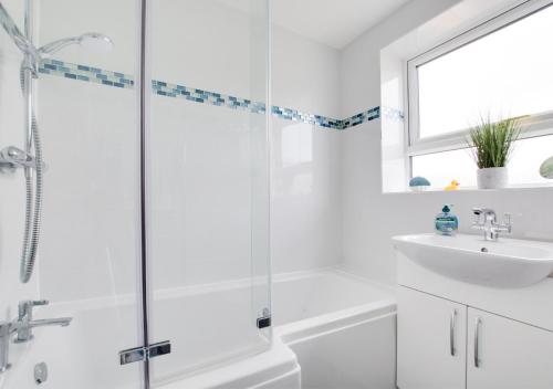 a white bathroom with a shower and a sink at Seascape in Walmer