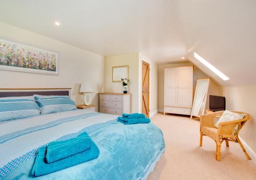 a bedroom with a large blue bed and a chair at Shuttleworth Lodge in Thursford