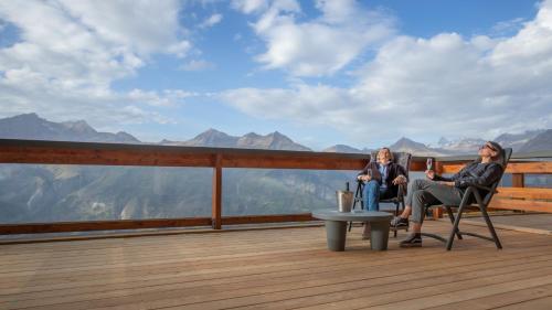 two women sitting on a deck with a view of mountains at La Cachette, Friendly Hotel & Spa in Arc 1600