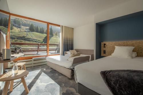 a hotel room with two beds and a large window at La Cachette, Friendly Hotel & Spa in Arc 1600