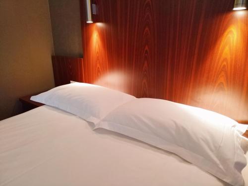 a bed with white sheets and a wooden head board at Milky Way Hotel in Budapest