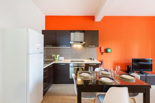 a kitchen with a table and a white refrigerator at Lovely, Spacious High Floor APT in central PV & AC by 360 Estates in Paceville