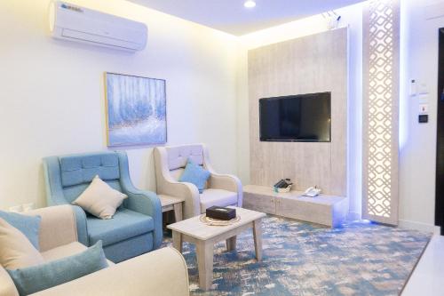 a living room with blue chairs and a tv at فندق واي هوتل in Abha