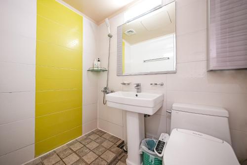 een badkamer met een wastafel, een toilet en een spiegel bij Mega Resort in Jeju-stad