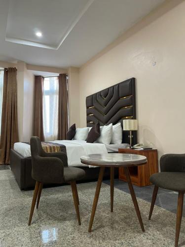 a bedroom with a bed and a table and chairs at De Silver Green Luxury Hotel in Abuja