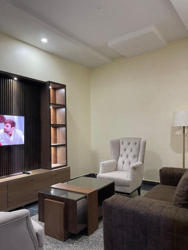 a living room with a couch and a tv at De Silver Green Luxury Hotel in Abuja