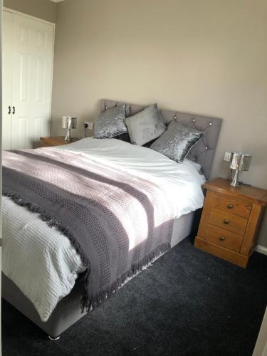 a bedroom with a large bed and a wooden nightstand at Peaceful Holiday Lodge with Hot Tub in Lincolnshire