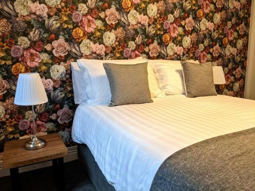 1 dormitorio con 1 cama y papel pintado con motivos florales en Racecourse Apartment, en Doncaster