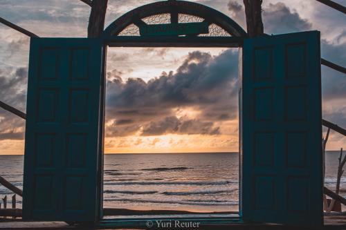 an open door to the beach at sunset at Pousada Cordel de Itaúnas in Itaúnas