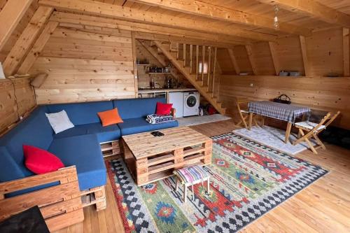 Cozy Forest Hut near Sarajevo في بال: غرفة معيشة مع أريكة زرقاء في كابينة خشب