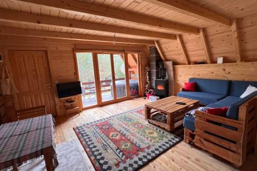 una sala de estar con un sofá azul en una cabaña de madera en Cozy Forest Hut near Sarajevo en Pale