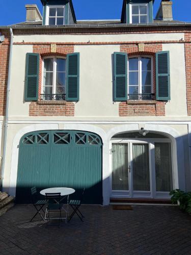 a building with a green garage door and a table at GÎTE DE LA MUSARDE in Villers-sur-Mer