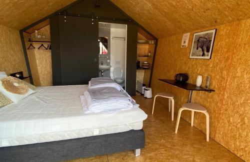 een slaapkamer met een bed en een tafel en stoelen bij Tenthuisje in het groen, een suite met eigen badkamer in Callantsoog