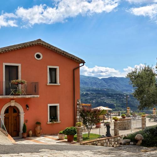 a red house with a balcony and mountains in the background at Piana la Gatta in Cusano Mutri