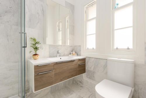 uma casa de banho com um WC, um lavatório e um espelho. em The Grassmarket Apartment em Edimburgo