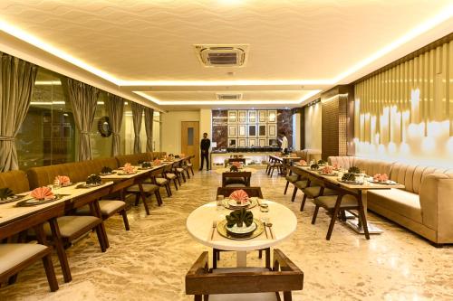 a restaurant with tables and chairs and a couch at Hotel Avalon Palms Agra in Agra