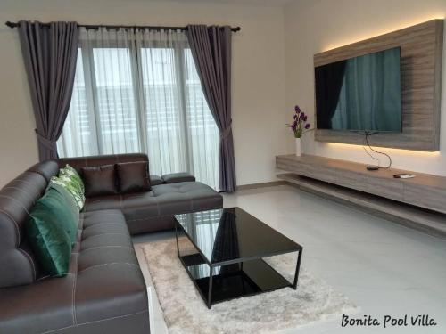 a living room with a leather couch and a tv at Bonita Pool Villa in Buriram