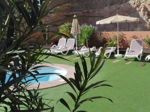 a yard with chairs and a pool and an umbrella at Casas de Tauro in La Playa de Tauro