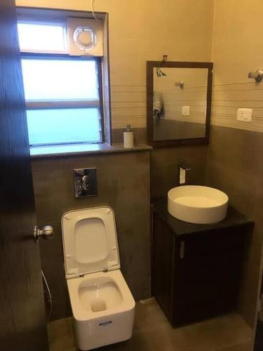 a bathroom with a toilet and a sink and a mirror at Olive Villa ECR 3BHK with Swimming Pool in Chennai