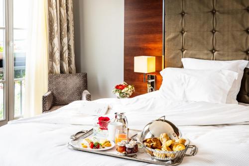 a breakfast tray on a bed with a tray of food at Relais Spa Val d'Europe in Chessy