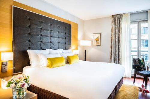 a hotel room with a large bed with yellow pillows at Relais Spa Chessy Val d'Europe in Chessy