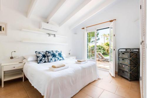 a white bedroom with a bed and a window at Villa Hércules 115 Binidali in Cap d'en Font