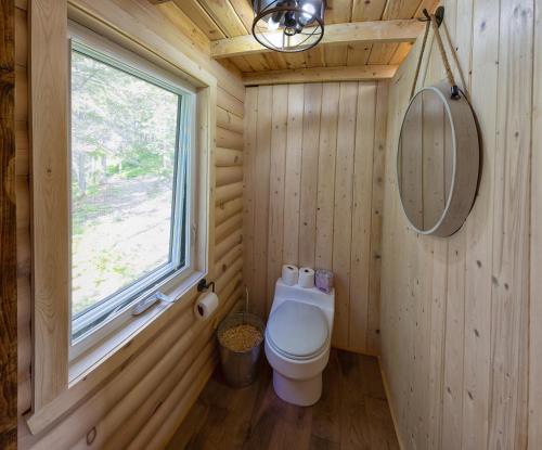 a bathroom with a toilet in a wooden wall at Les Racines du p'tit Isidore in Rouyn-Noranda