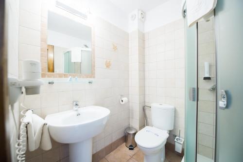 a white bathroom with a sink and a toilet at Pensiunea Turistica Villa Ermitage in Buşteni