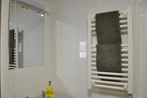 a bathroom with a towel rack over a sink at Heart of the village Cotswold Cottage in Crudwell. in Crudwell