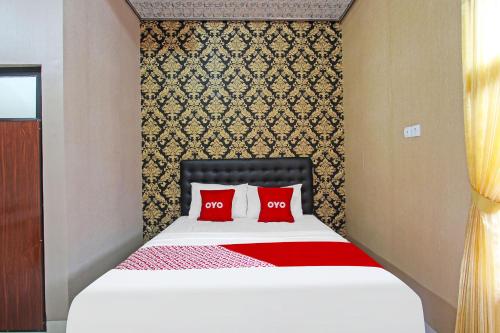 a bedroom with a bed with two red pillows at OYO 91842 Tahesa Guesthouse Syariah in Cilacap
