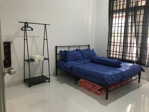 Bett mit blauen Kissen in einem weißen Zimmer in der Unterkunft A Comfortable Home (Haura Homestay Kemaman) in Cukai