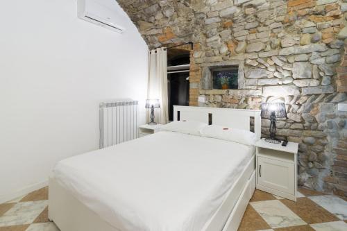 a bedroom with a white bed and a stone wall at BERGAMO art in Bergamo