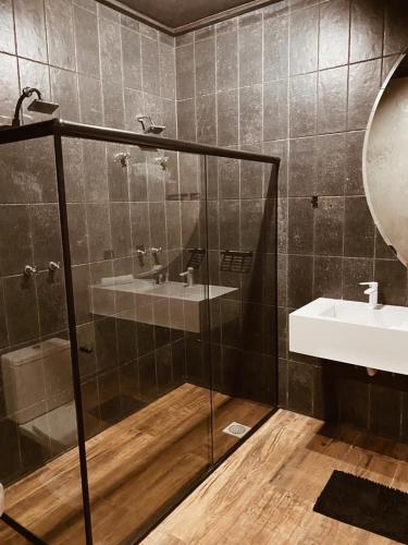 a bathroom with a glass shower and a sink at Pousada Cafe Poesia in Campos do Jordão