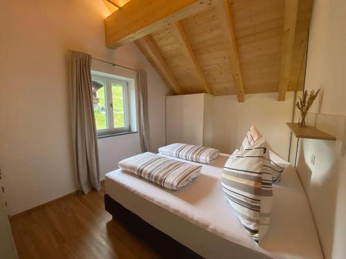 Zimmer mit einem Bett mit Kissen und einem Fenster in der Unterkunft 'dasBergblick' in Altaussee