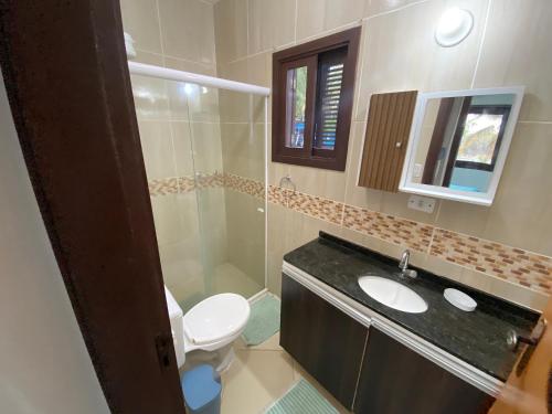 a bathroom with a toilet and a sink and a mirror at Apto no centro de Tibau com vista para lagoa/mar in Pipa