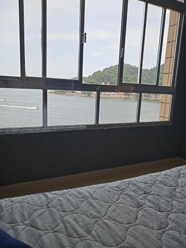 a bedroom with a bed and a view of the water at Lar de férias in São Vicente