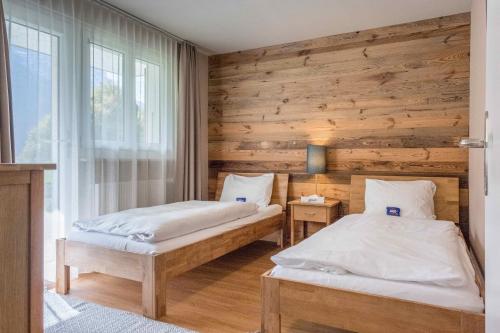 Duas camas num quarto com uma parede de madeira em Apartment Mühlegaden - GRIWA RENT AG em Grindelwald
