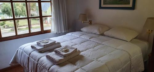 a bedroom with a white bed with towels on it at Cabañas Trabunche in San Martín de los Andes
