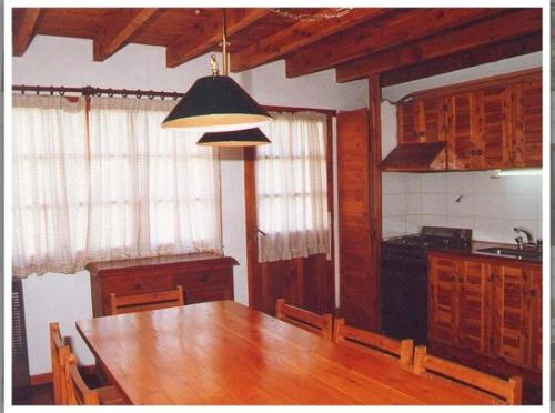 a kitchen with a wooden table with chairs and a lamp at Cabañas Trabunche in San Martín de los Andes