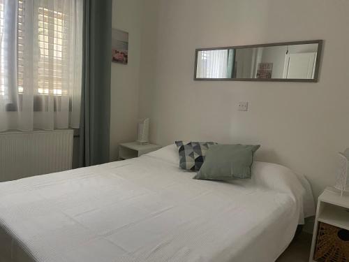 a white bed in a bedroom with a mirror at LE CAROUBIER splendid 3 bedrooms bungalow in Zanaja