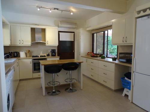 a kitchen with white cabinets and bar stools in it at LE CAROUBIER splendid 3 bedrooms bungalow in Zanaja