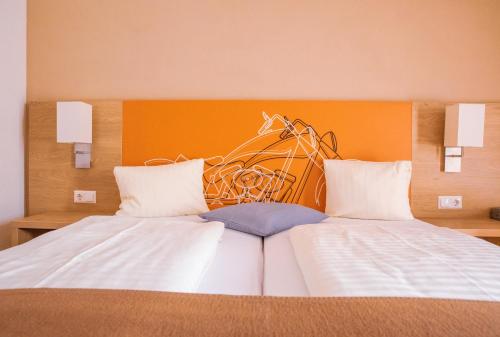 a bedroom with two beds with an orange headboard at Hotel Kuchlerwirt in Treffen