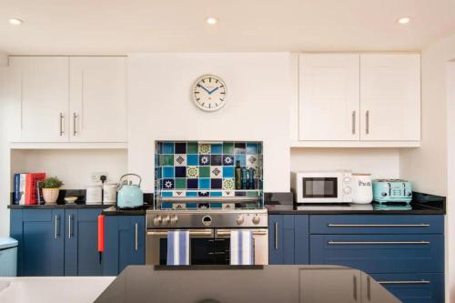 a kitchen with blue cabinets and a clock on the wall at Quirky 1 Bedroom Apartment in Kemptown in Brighton & Hove