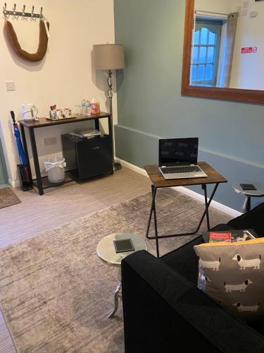 a living room with a couch and a table with a laptop at Self-contained, Framlingham Snug, Private Parking, no cooking facilities in Framlingham