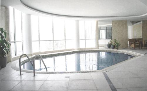 a large swimming pool in a large room with windows at Butterfly Residence in Manama