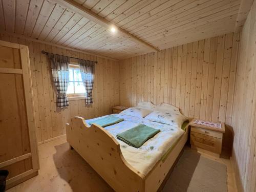 1 dormitorio con 1 cama en una habitación de madera en Kilge Alm, en Großkirchheim