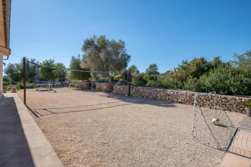 a tennis court with a net and a stone wall at Finca Son Puca in Petra