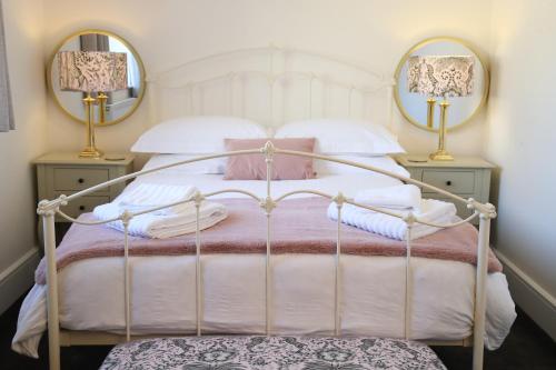 a bedroom with a bed with two lamps and two mirrors at Burgess Yard 2-bedroom cottage, Bath in Bath