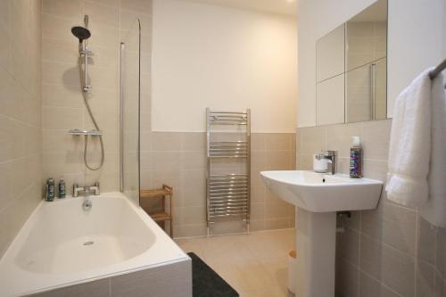 y baño con lavabo, bañera y ducha. en Burgess Yard 2-bedroom cottage, Bath en Bath