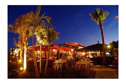 a restaurant with tables and chairs and palm trees at night at VILLA VALENTINA in Mataró